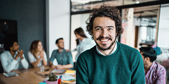 Glad man i grön tröja i ett mötesrum