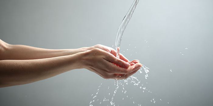 Händer som fångar upp rinnande vatten