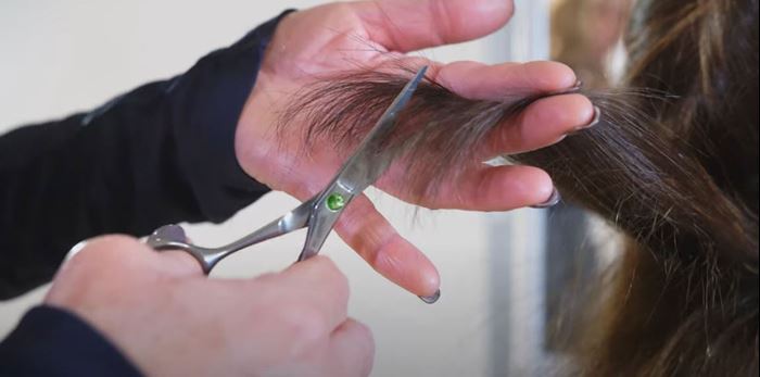 Närbild på hår som en frisör klipper med sax