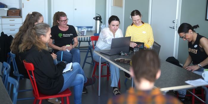 Flera personer sitter runt ett bord och har möte.