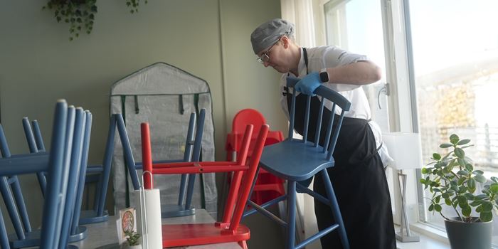 Person som lyfter upp stolar och hänger dem på bordskanten