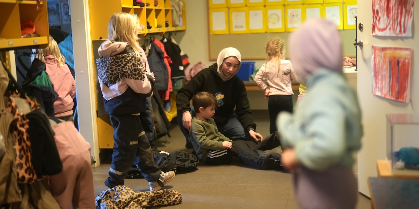 Förskolepersonal hjälper barn med påklädning