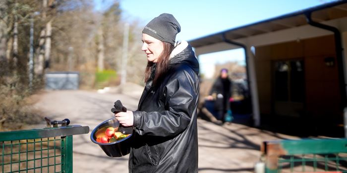 Kvinna som står utomhus med en skål med frukt i handen