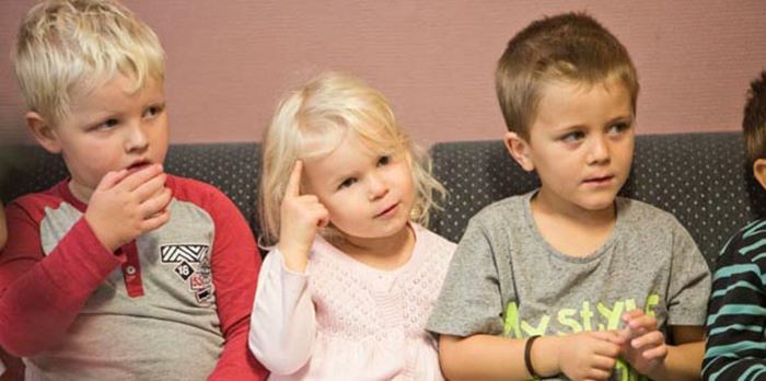 Tre förskolebarn som sitter i en soffa