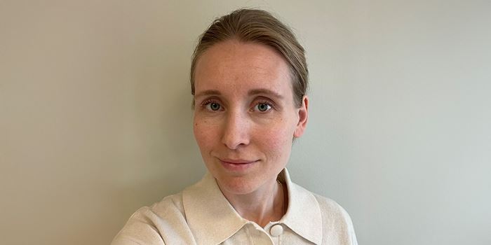 En kvinna i vit tröja som ler mot kameran.