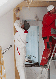 Två målare som arbetar i takhöjd inomhus