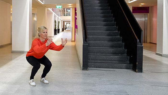 Kvinna gör benböj i ett trapphus