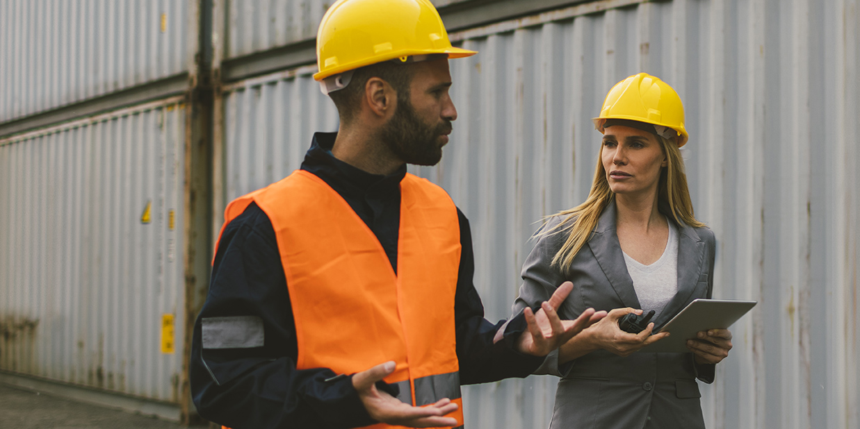 Två personer i samtal på en byggarbetsplats