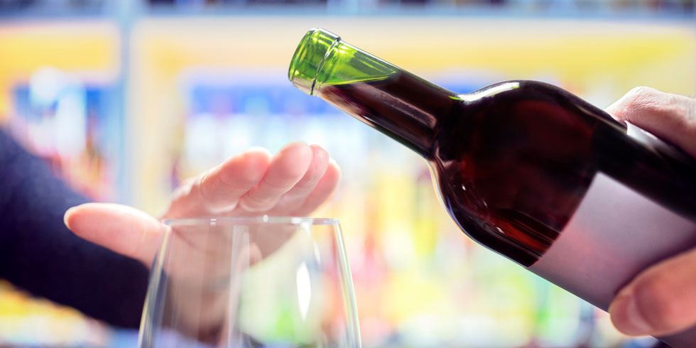 Vinflaska och en hand som håller för glaset
