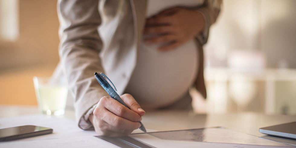 Gravid kvinna vid skrivbord