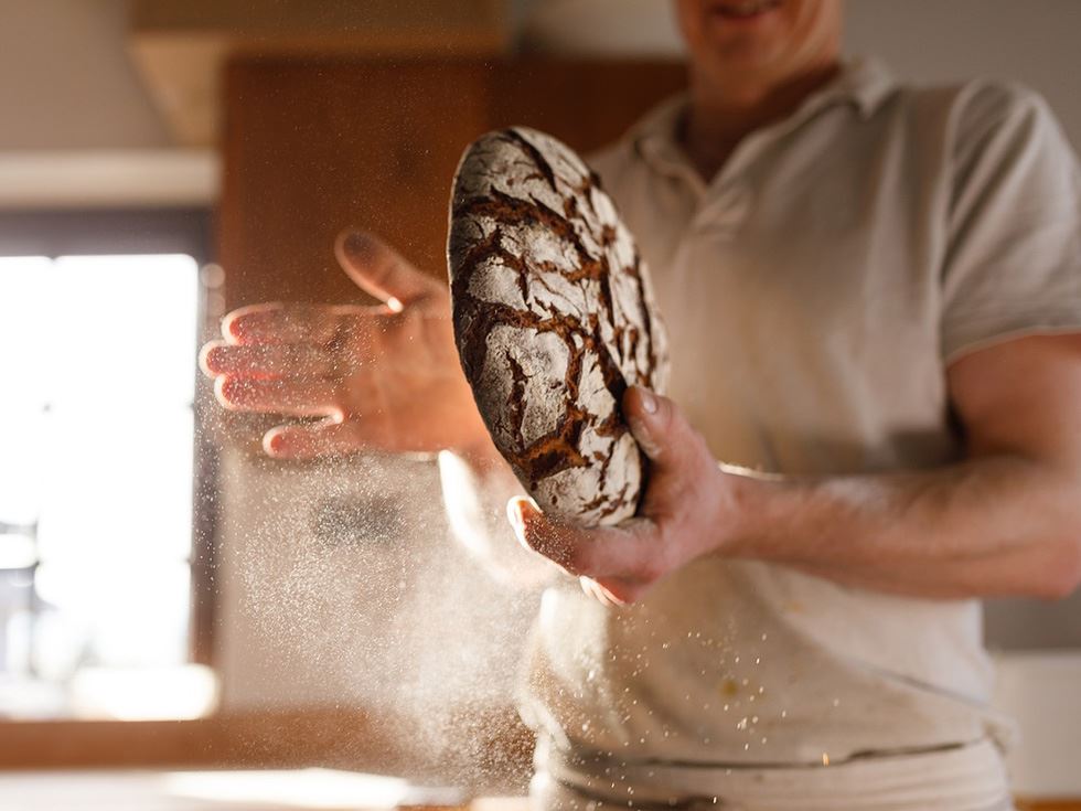 En bagare med ett bröd i handen.