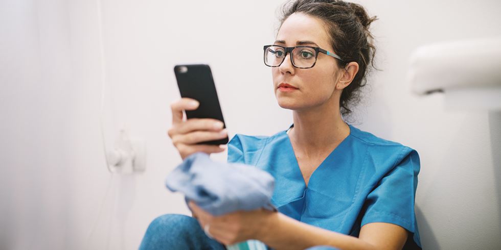 Ung sjuksköterska kollar på sin mobil