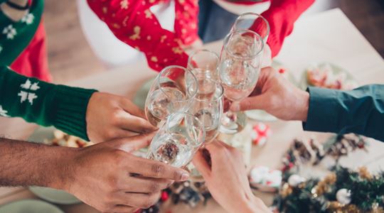 Armar med glas i händerna som sträcks fram mot mitten för att skåla.