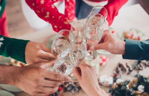 Armar med glas i händerna som sträcks fram mot mitten för att skåla.
