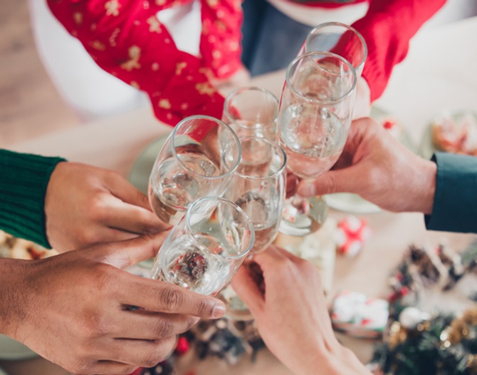 Armar med glas i händerna som sträcks fram mot mitten för att skåla.