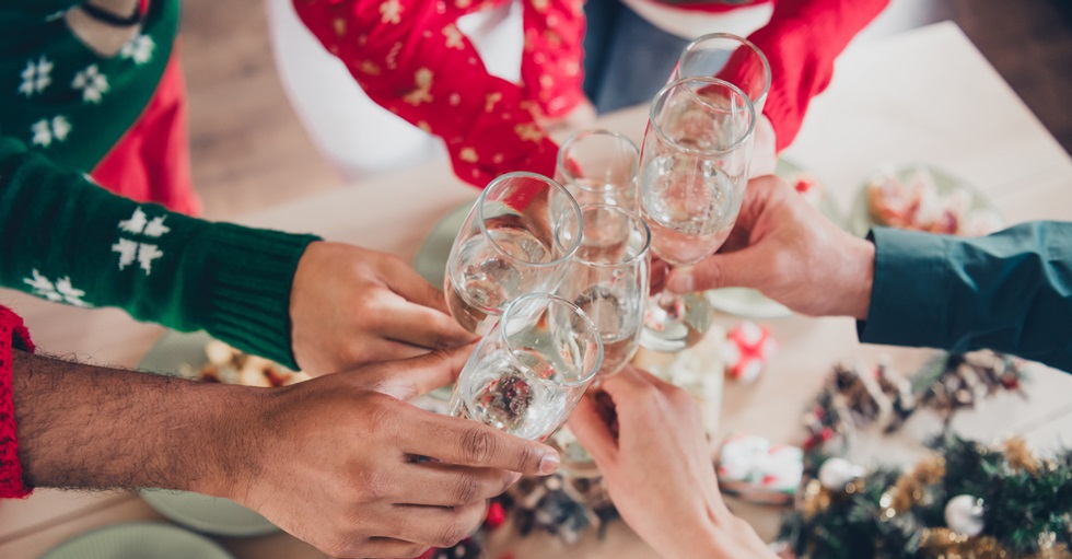 Armar med glas i händerna som sträcks fram mot mitten för att skåla.