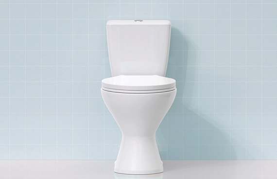 En vit toalett mot ljusblått kakel.