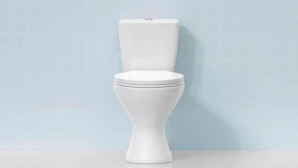 En vit toalett mot ljusblått kakel.