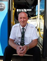 Porträtt av Himzo Ahmic som sitter på trappen vid framdörren på en buss.