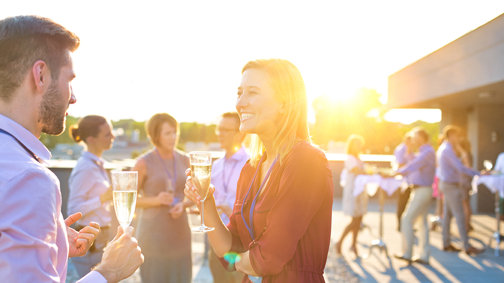 En personalfest där man ser kollegor prata med ett glas vin i handen.