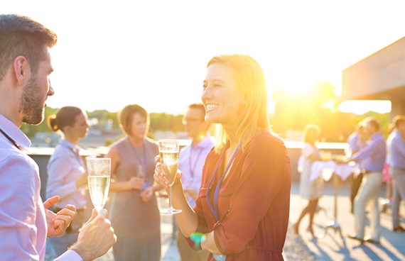 En personalfest där man ser kollegor prata med ett glas vin i handen.