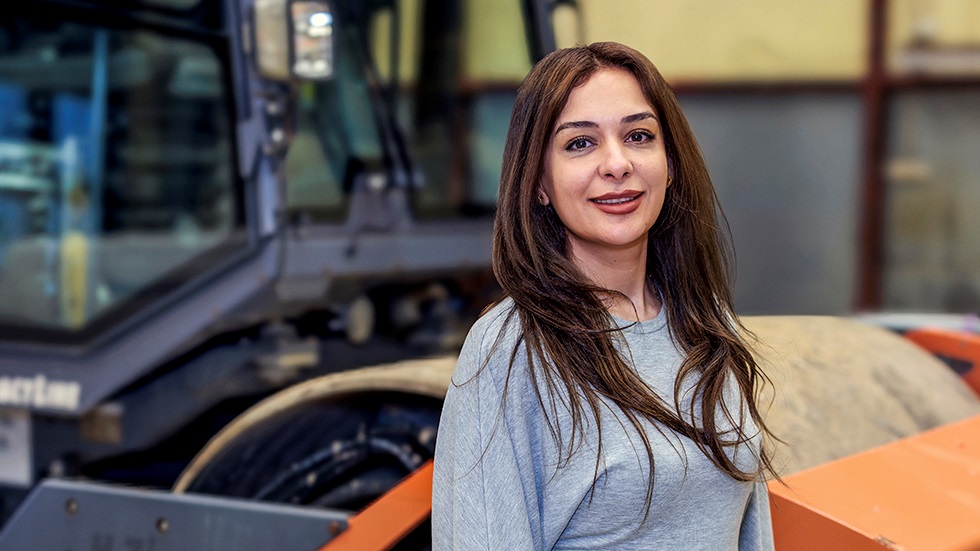 Kvinna med brunt hår ler mot kameran