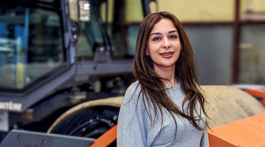 Kvinna med brunt hår ler mot kameran