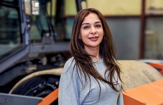 Kvinna med brunt hår ler mot kameran