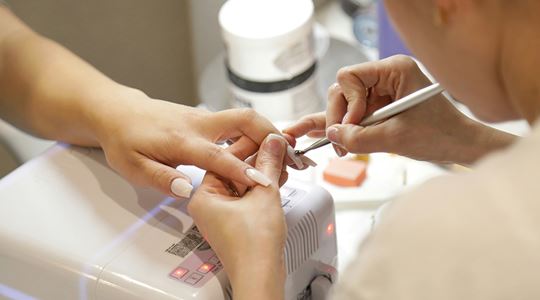 En kvinna får sina naglar fixade på en nagelsalong.