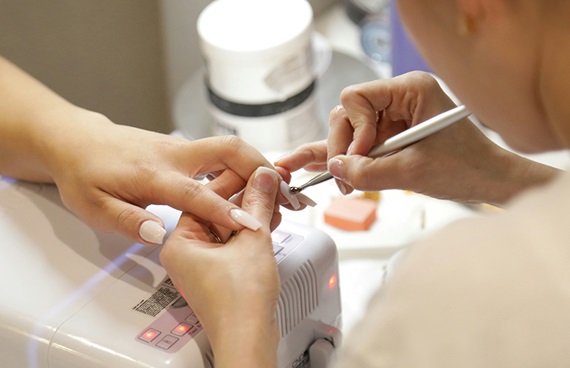 En kvinna får sina naglar fixade på en nagelsalong.