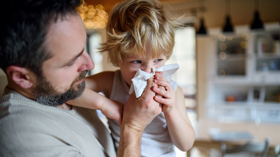 En pappa bär sitt sjuka barn på armen.