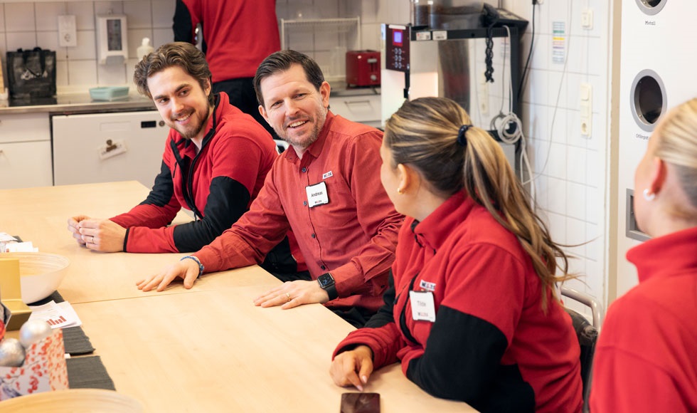 Butikschefen Andreas Selsborg sitter med några av de anställda vid ett bord i personalrummet.