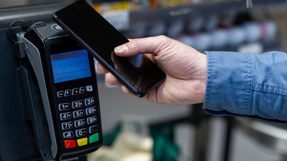 En person betalar med sin mobil i en självscanningskassa
