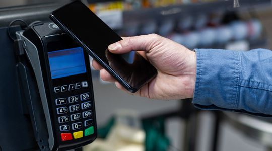 En person betalar med sin mobil i en självscanningskassa