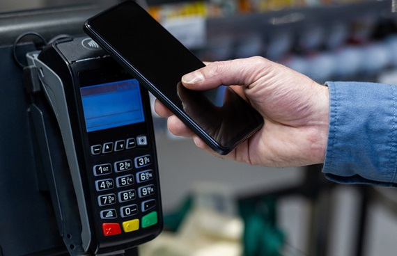 En person betalar med sin mobil i en självscanningskassa