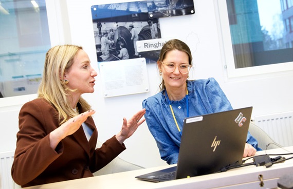 Petronella Schröder (t.h.) och hennes kollega Desirée Comstedt sitter framför en laptop vid ett skrivbord och diskuterar.