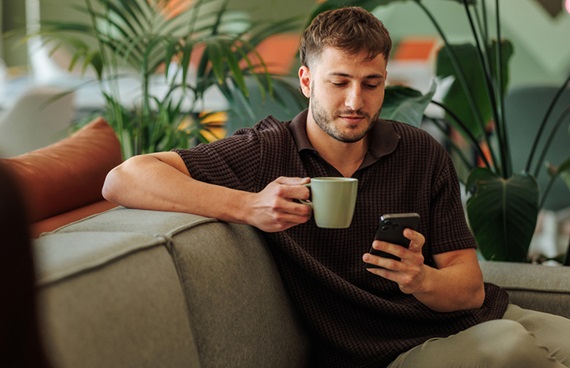 En man sitter och tittar på sin mobil under en fikapaus på jobbet.