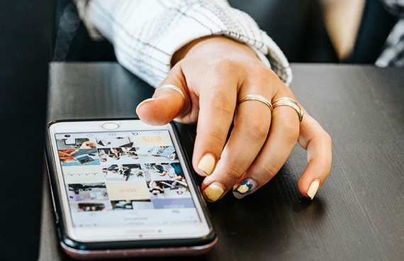 En ung kvinna scrollar bland bilder i mobilen.