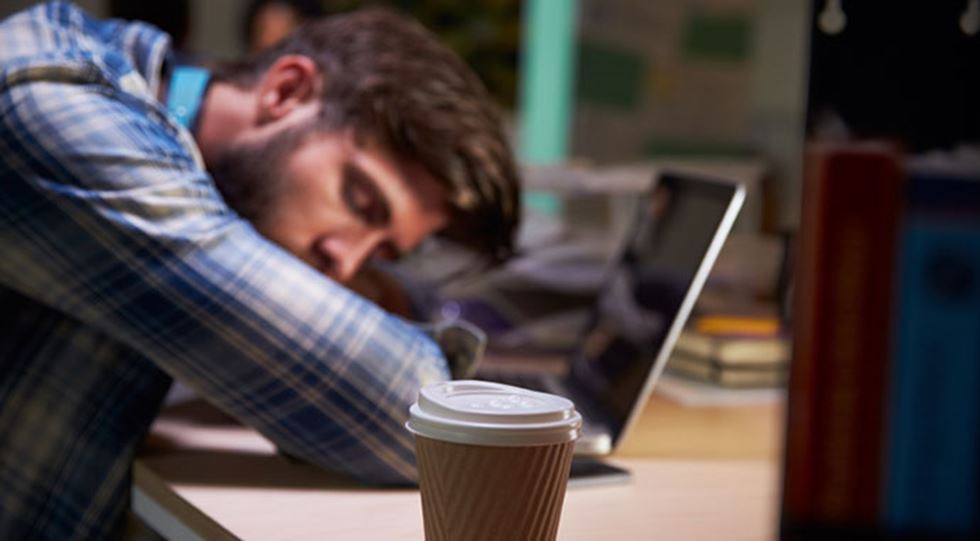 Man sover vid sin laptop.
