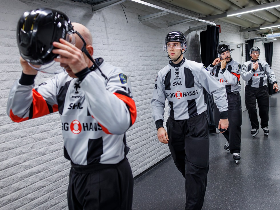 Fyra hockeydomare på led, på väg in till match.