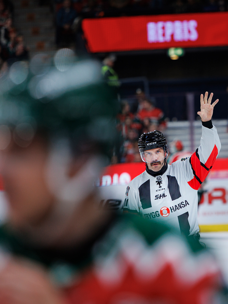 Mikael Holm dömer en fem minuters utvisning. Han sträcker upp armen och visar fem fingrar.