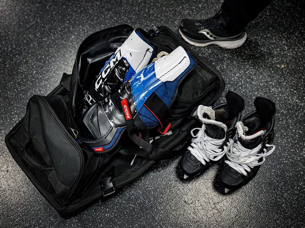 Närbild på väska med utrustning, och ett par skridskor som står bredvid.