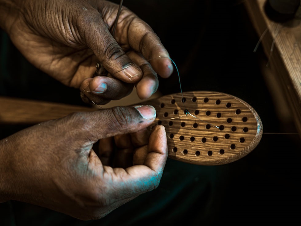 Närbild på händer som binder en borste.