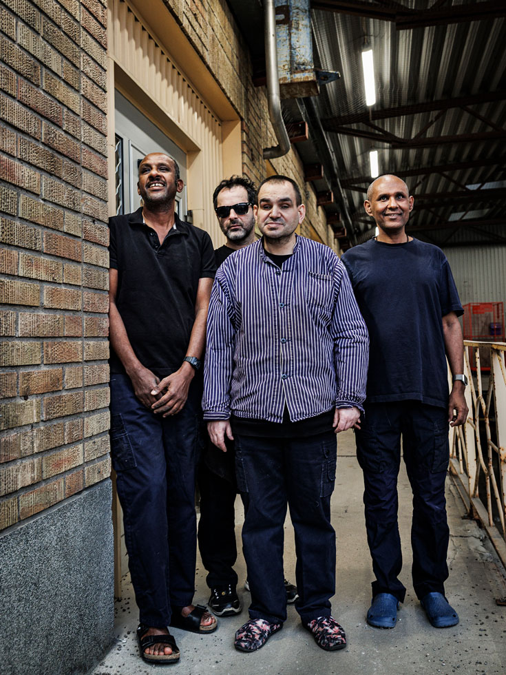 Fyra av de anställda står uppställda inne i fabrikslokalen.