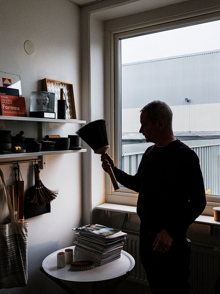 Silhuett av vd:n Richard Sparrenhök med en kvast i handen framför ett fönster.